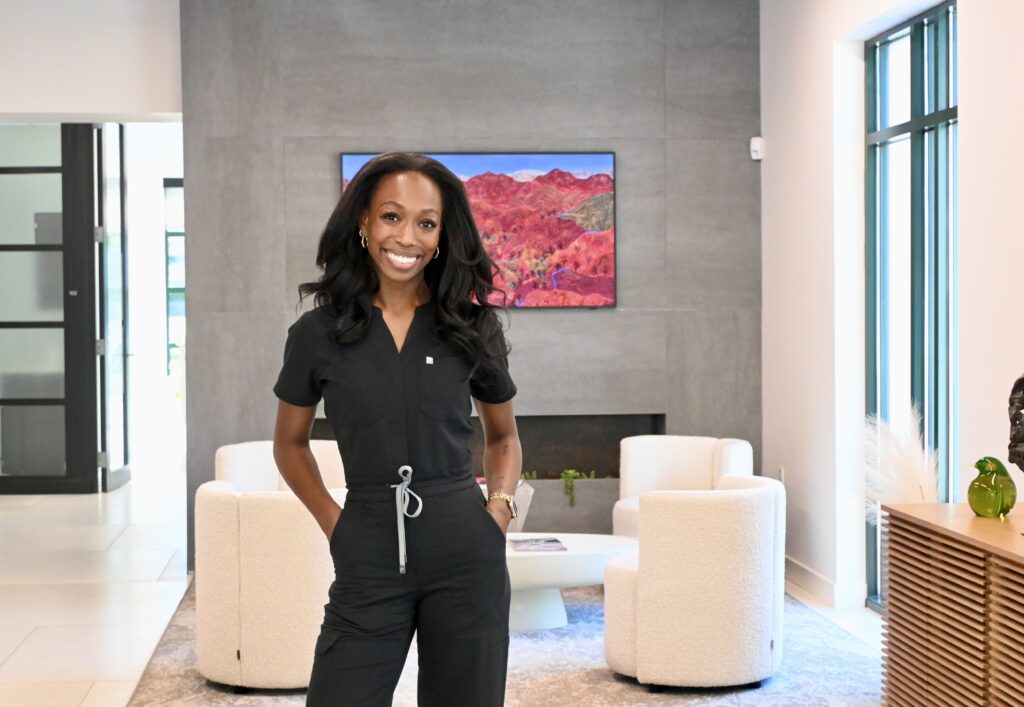 Genesy Smith in black scrubs standing in the lobby at NC Implants and Periodontics.